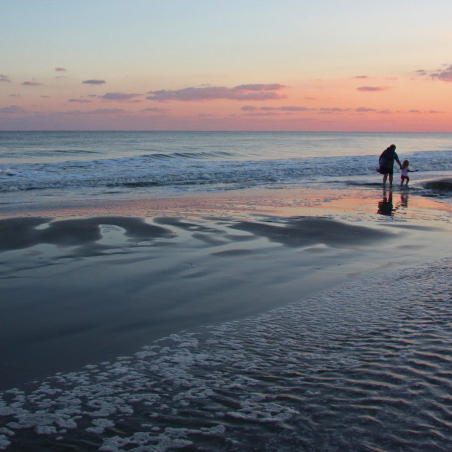 An adult and child go on a final shelling expedition as the sun sets on Isle of Palms, South Carolina.